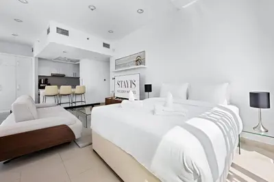 a white bedroom with a large bed and chairs at Stayis -Studio in Twisted Tower Dubai Marina in Dubai