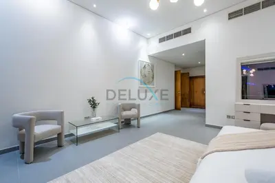 a bedroom with a bed and two chairs and a table at Waterfront 2BR Apartment with Assistant Room in Dream Palm Residence, Palm Jumeirah by Deluxe Holiday Homes in Dubai