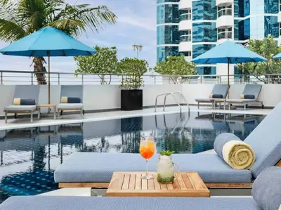 a swimming pool with a drink on a table next to a hotel at Duplex Suite in 5-Star Movenpick Hotel in Dubai