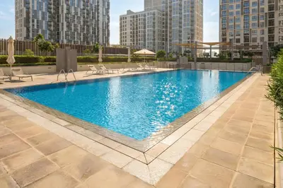 a large swimming pool in a city with tall buildings at Nicely Furnished 2BR Home in Dubai Hills in Dubai