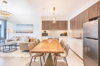 a kitchen and living room with a wooden table and chairs at Nicely Furnished 2BR Home in Dubai Hills in Dubai