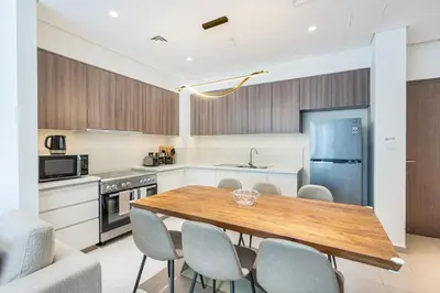 a kitchen and dining room with a wooden table and chairs at Nicely Furnished 2BR Home in Dubai Hills in Dubai
