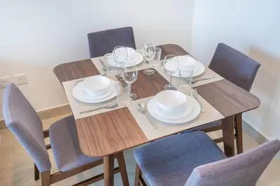 a wooden table with chairs and plates and wine glasses at RH - Stunning Canal View 01 BR with Top amenities, newly furnished in Dubai