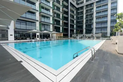 a large swimming pool in front of a building at Bright & Cozy 1br Jvc Balcony Free Parking in Dubai