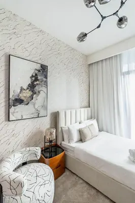 a white bedroom with a bed and a chair at Nasma Luxury Stays - Trendy & Stylish Living Studio at Azizi Riviera 41 in Dubai