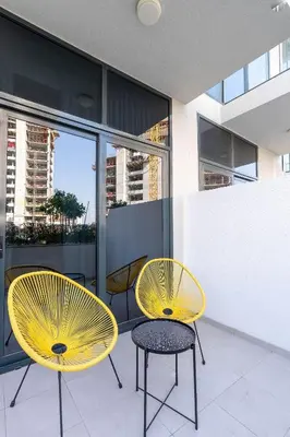 two yellow chairs and a table on a balcony at Nasma Luxury Stays - Trendy & Stylish Living Studio at Azizi Riviera 41 in Dubai