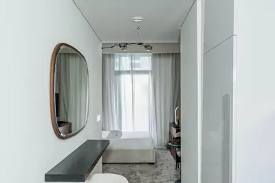 a white room with a mirror and a bed at Nasma Luxury Stays - Trendy & Stylish Living Studio at Azizi Riviera 41 in Dubai