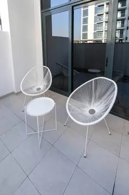two white chairs and a table on a balcony at Nasma Luxury Stays - Dreamy Getaway Unwind in a Modern Dubai Studio in Dubai