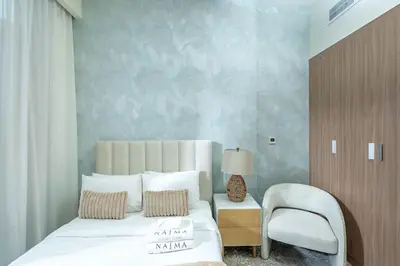 a bedroom with a white bed and a chair at Nasma Luxury Stays - Dreamy Getaway Unwind in a Modern Dubai Studio in Dubai
