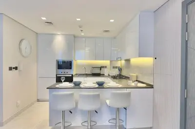 a kitchen with two bar stools and a counter at Relaxing 2BR Escape with Private Pool Samana GA by Vibel in Dubai