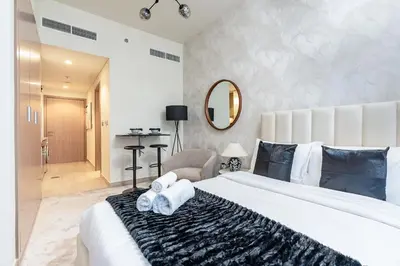 a bedroom with a large white bed and a mirror at Nasma Luxury Stays - Cozy Urban Studio at Azizi Riviera 43 in Meydan in Dubai