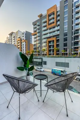 a balcony with two chairs and a table and some buildings at Nasma Luxury Stays - Cozy Urban Studio at Azizi Riviera 43 in Meydan in Dubai