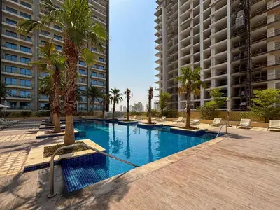 a swimming pool with palm trees and buildings at Frank Porter - Damac Ghalia Tower - Studio in Dubai