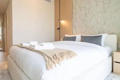 a white bed with a blanket on top of it at Downtown Views Open Burj View 34th Floor 2BD in Dubai