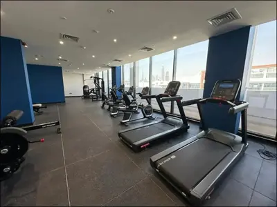 a gym with rows of treadmills and elliptical machines at Dubai Galaxy in Azizi Riviera Luxury Studio in Dubai