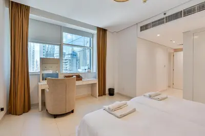 a bedroom with two beds and a desk and a window at 3BR Apartment in Business Bay with Pool & Canal Walk in Dubai