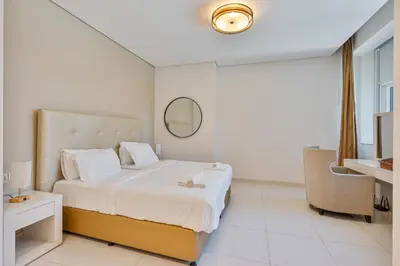 a white bedroom with a bed and a chair at 3BR Apartment in Business Bay with Pool & Canal Walk in Dubai