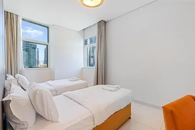 two beds in a room with a window at 3BR Apartment in Business Bay with Pool & Canal Walk in Dubai