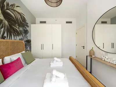 a bedroom with a white bed with a mirror at Dar Mama - Cozy modern apartment in Golf Vita, Dubai in Dubai