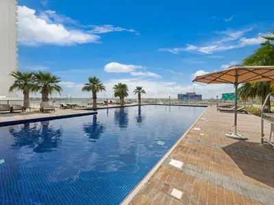 a swimming pool with palm trees and the beach at Dar Mama - Cozy modern apartment in Golf Vita, Dubai in Dubai