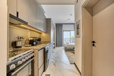 a kitchen with stainless steel appliances and a hallway at Chic and Bright Studio in Meydan in Dubai