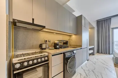 a kitchen with a stove and a washing machine at Chic and Bright Studio in Meydan in Dubai