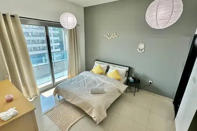 a bedroom with a bed with yellow pillows and a window at Himalaya Holiday Homes 1 BHK Apartment in Dubai