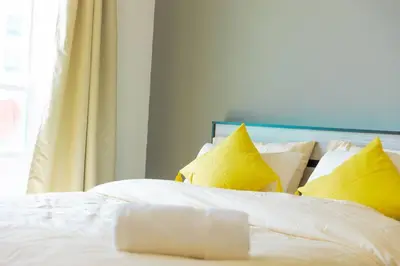 a bed with white sheets and yellow pillows at Himalaya Holiday Homes 1 BHK Apartment in Dubai