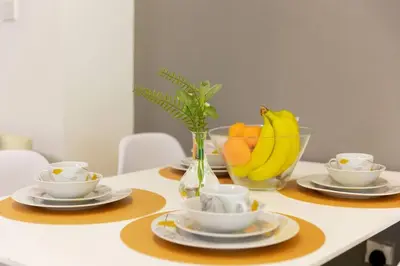 a table with plates and cups and a bowl of fruit at Himalaya Holiday Homes 1 BHK Apartment in Dubai