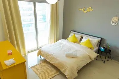a bedroom with a bed with yellow pillows and a window at Himalaya Holiday Homes 1 BHK Apartment in Dubai