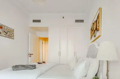 a white bedroom with a bed and a lamp at Elegant 2 Bedroom Apartment in Dubai Marina- Just 1 Min walk from JBR Beach in Dubai
