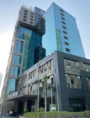 a large glass building with a palm tree in front of it at Cozy Hideaway-Damac Cour Jardin near Dubai Mall in Dubai