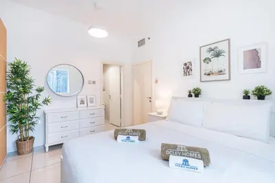 a white bedroom with a large bed and a mirror at Beautiful Home at the Heart of Marina in Dubai