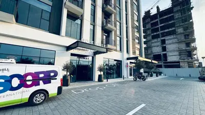 a bus parked in front of a building at Studio Hotel Apartment Brand New Azizi Riv 14 in Dubai