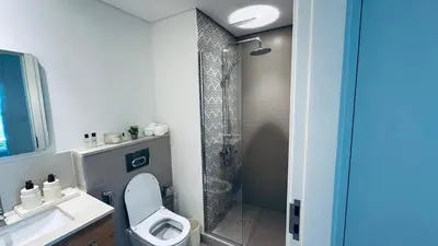 a bathroom with a shower and a toilet and a sink at Studio Hotel Apartment Brand New Azizi Riv 14 in Dubai