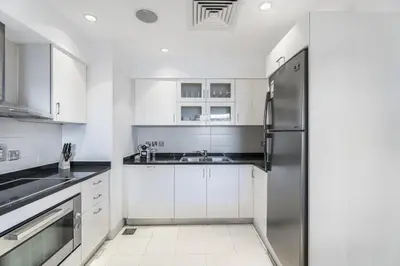 a kitchen with white cabinets and a stainless steel refrigerator at Oceana Baltic Palm West Beach Views 3 bd Sleeps 7 in Dubai