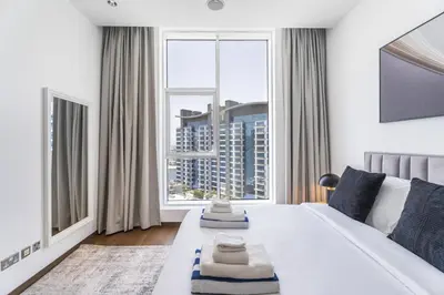 a bedroom with a large white bed with a large window at Oceana Baltic Palm West Beach Views 3 bd Sleeps 7 in Dubai