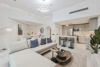a living room with a white couch and a kitchen at Luxury at Beachside Al Sultana Jumeirah Shoreline - DVH Holiday Homes in Dubai