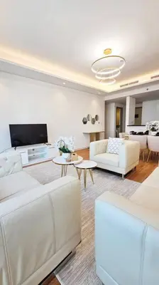 a living room with white furniture and a tv at Luxury 2BR Midtown Apartment in Dubai
