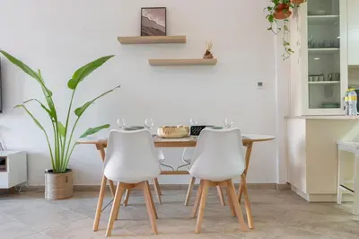 a kitchen with a wooden table and two white chairs at StayShort - Cozy 1-Bedroom Apartment for 5 in Motor City! in Dubai