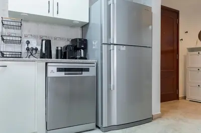 a kitchen with a white refrigerator and a dishwasher at StayShort - Cozy 1-Bedroom Apartment for 5 in Motor City! in Dubai