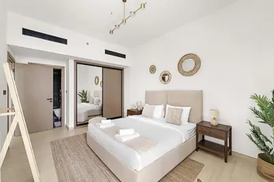 a white bedroom with a white bed and a mirror at Vayk - Modern 2BR Apartment in Dubai