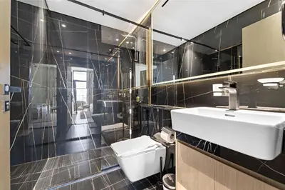 a black tiled bathroom with a sink and a toilet at Vayk - Modern 2BR Apartment in Dubai