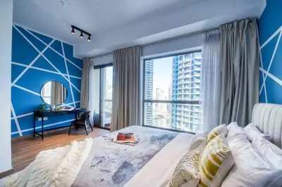 a bedroom with blue walls and a large window at The Smart Concierge - Bahar 6 in Dubai