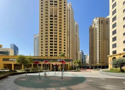 a courtyard with umbrellas in a city with tall buildings at The Smart Concierge - Bahar 6 in Dubai