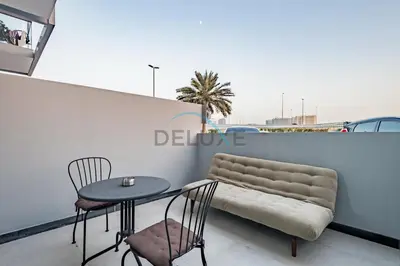 a table and two chairs and a couch on a balcony at Modern Loft-Style Studio at Aria Residence, Jumeirah Village Circle by Deluxe Holiday Homes in Dubai