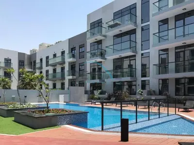 an apartment building with a swimming pool in front of it at Modern Loft-Style Studio at Aria Residence, Jumeirah Village Circle by Deluxe Holiday Homes in Dubai