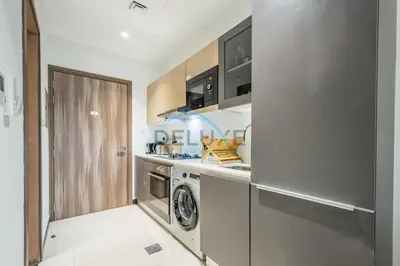 a kitchen with a washer and dryer in a room at Modern Loft-Style Studio at Aria Residence, Jumeirah Village Circle by Deluxe Holiday Homes in Dubai