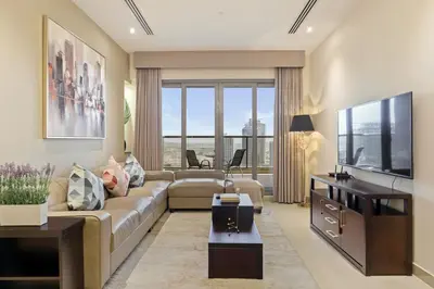 a living room with a couch and a television at Cozy 2BR in Elite Downtown Residence with Canal view in Dubai