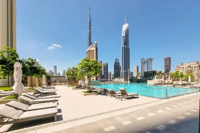a swimming pool with lounge chairs and a city skyline at Peaceful Dunes 1 - Burj Khalifa & Dubai Mall in Dubai